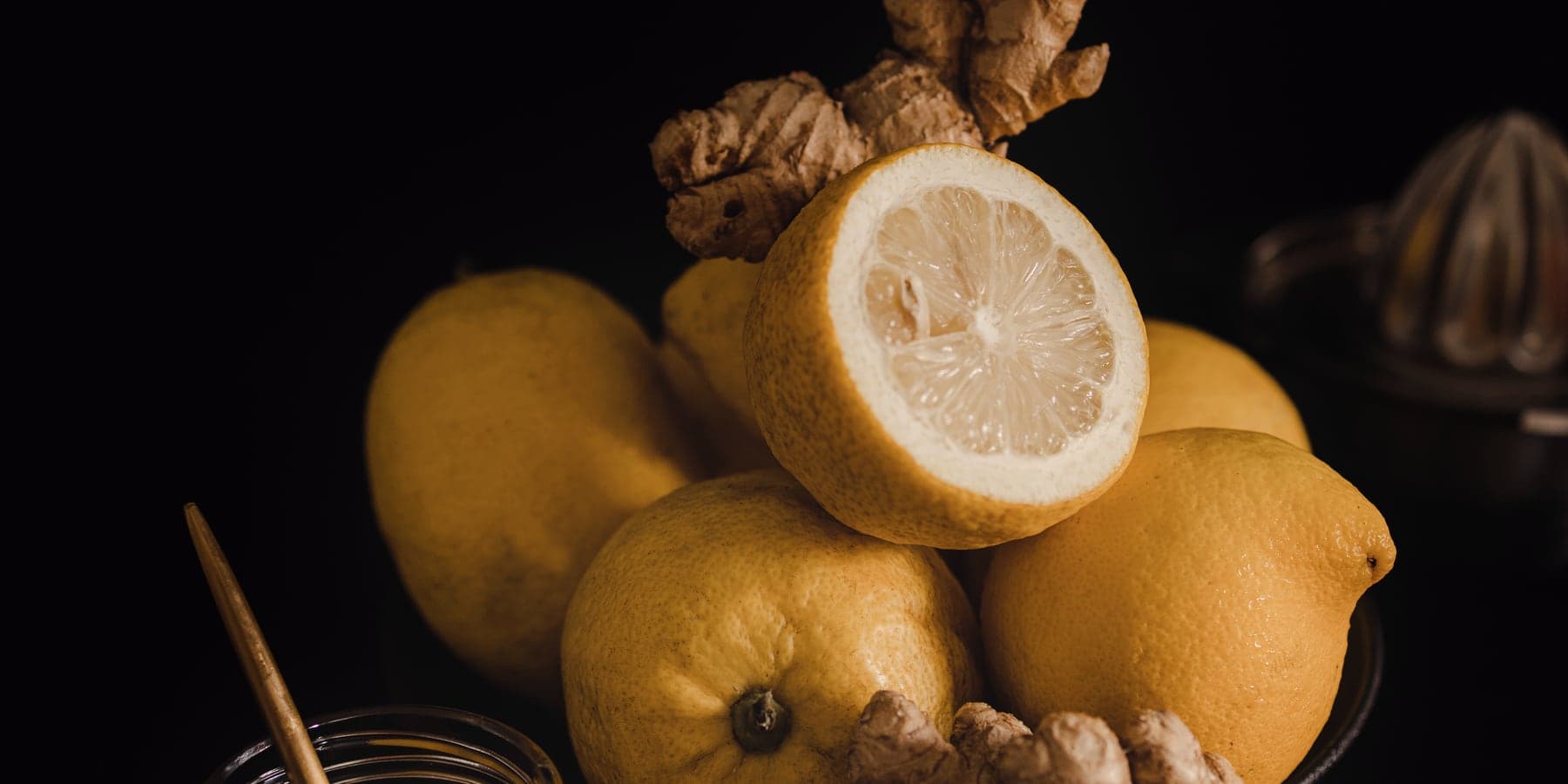 Lemons and fresh ginger lit against a dark background